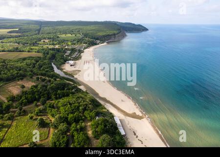 Blick aus der Vogelperspektive auf den goldenen Sand, der auf das türkisfarbene Wasser am Vaya Beach trifft, eingerahmt von üppigen grünen Wäldern und Klippen, Vaya Beach, Burgas, Bulgarien. Stockfoto
