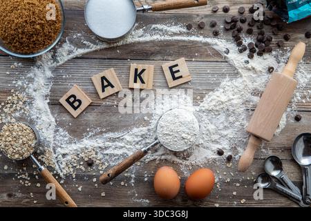 Ein Backhintergrundkonzept mit dem Wort Bake auf Holzfliesen in der Mitte. Stockfoto