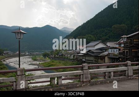 Die Shinbashi-Brücke (新橋) und der Fluss Yoshida führen an einem trüben Sommertag in der Präfektur Gifu, Japan durch die Bergstadt Gujo-Hachiman (郡上八幡). Stockfoto