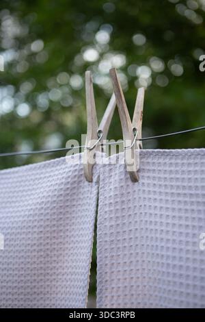 Farbenfrohe Textilhandtücher hängen draußen an einer Wäscheleine. Frisch gewaschener Stoff trocknet bei natürlichem Sonnenlicht mit Wäscheständer, weicher Textur, Sommer-atm Stockfoto