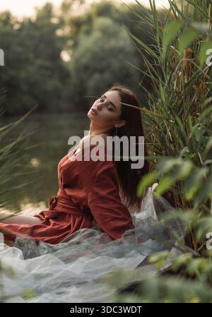 Stimmungsvolle Nahaufnahme einer Frau, die in einem Boot ruht und einen friedlichen Moment genießt. Traumhafter Sommerabend am Wasser mit weichem natürlichem Licht und üppigem grün Stockfoto