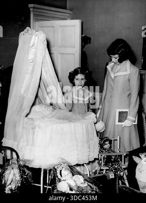 Prinzessinnen sehen ihr eigenes Bett bei der Ausstellung -- Prinzessin Elizabeth (rechts *****) Prinzessin Margaret Rose sieht sich das ***** an Beide werden als Babys verwendet und welche Stockfoto