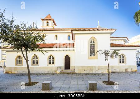 Blick auf die Pfarrkirche in Armacao de Pera, Algarve, Portugal, mit weiß getünchten Wänden, traditionellem Ziegeldach, Glockenturm mit Uhr und A Stockfoto