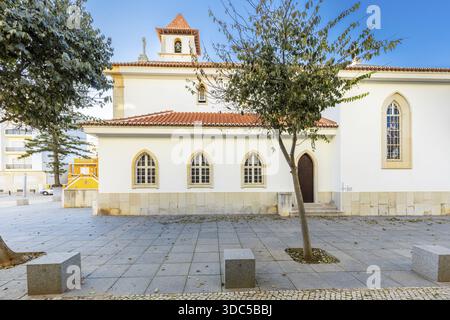 Blick auf die Pfarrkirche in Armacao de Pera, Algarve, Portugal, mit weiß getünchten Wänden, traditionellem Ziegeldach, Glockenturm mit Uhr und A Stockfoto