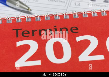 Nahaufnahme eines roten Kalenders für 2026 mit Spiralbindung und blauem Stift, Tagebuch Stockfoto