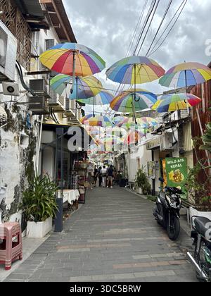 Lebhafte und farbenfrohe Gasse mit hängenden Sonnenschirmen und Gassen-Geschäften Stockfoto