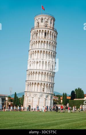 Pisa, Italien - 26. Juni 2025: Ein großer Blick auf den Schiefen Turm von Pisa, der sich über dem Rasen erhebt, während große Gruppen von Touristen spazieren gehen, anstehen und Fotos machen Stockfoto