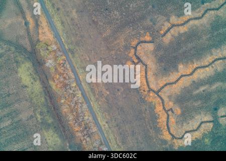 Von oben nach unten auf eine lange militärische Verteidigungslinie mit Gräben, die durch ein Feld schneiden. Die Erdarbeiten veranschaulichen Kampftechnik und Befestigungsstrategien in der Ukraine-Konfliktzone. Stockfoto