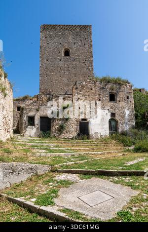 Craco, Italien-25. april 2025: Vertikales Foto des normannischen Turms zwischen den Ruinen der Geisterstadt Craco an einem Sommertag Stockfoto