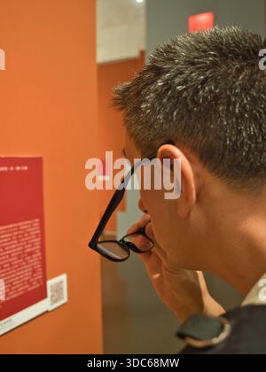 Peking-Pekín-China-14. August 2018, Nahaufnahme eines Teilnehmers, der eine Tafel oder informative Texttafel auf einer Ausstellung in einem modernen Museum oder einer Kunstgalerie liest Stockfoto