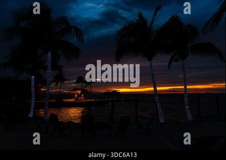Sonnenuntergang am Marathon Key mit Palmen im Vordergrund und buntem Himmel über dem Horizont im Hintergrund, Florida Stockfoto