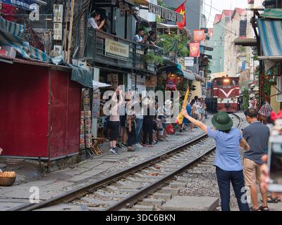 hanoi-Vietnam-10. August 2019, Touristen drängen sich auf der schmalen Bahnstraße (phố Đường Tàu) in Hanoi, Vietnam, und beobachten einen Zug, der sich nähert. Diese einzigartige Residenz Stockfoto