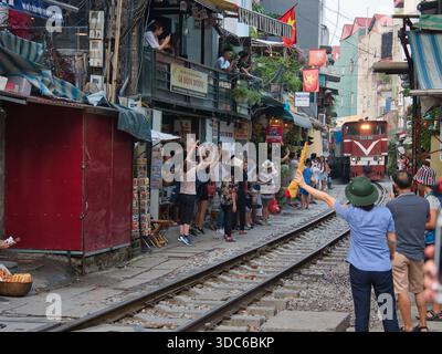 hanoi-Vietnam-10. August 2019, Touristen drängen sich auf der schmalen Bahnstraße (phố Đường Tàu) in Hanoi, Vietnam, und beobachten einen Zug, der sich nähert. Diese einzigartige Residenz Stockfoto