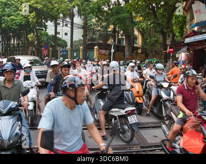 hanoi-Vietnam-10. August 2019, dichte Verkehrsstaus mit zahlreichen Motorrädern und Motorrollern, die Eisenbahngleise in einem geschäftigen Stadtgebiet von Hano überqueren Stockfoto