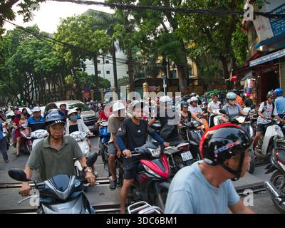 hanoi-Vietnam-10. August 2019, dichte Verkehrsstaus mit zahlreichen Motorrädern und Motorrollern, die Eisenbahngleise in einem geschäftigen Stadtgebiet von Hano überqueren Stockfoto
