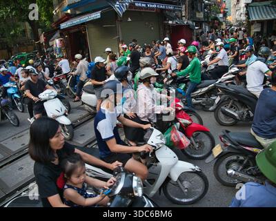 hanoi-Vietnam-10. August 2019, dichte Verkehrsstaus mit zahlreichen Motorrädern und Motorrollern, die Eisenbahngleise in einem geschäftigen Stadtgebiet von Hano überqueren Stockfoto