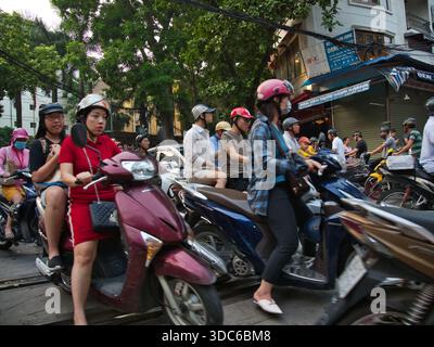 hanoi-Vietnam-10. August 2019, dichte Verkehrsstaus mit zahlreichen Motorrädern und Motorrollern, die Eisenbahngleise in einem geschäftigen Stadtgebiet von Hano überqueren Stockfoto
