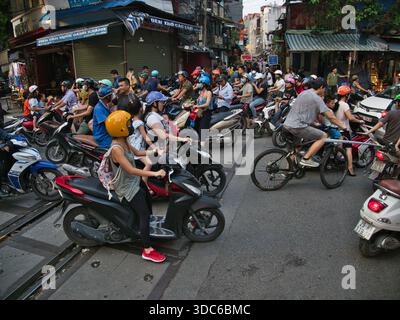 hanoi-Vietnam-10. August 2019, dichte Verkehrsstaus mit zahlreichen Motorrädern und Motorrollern, die Eisenbahngleise in einem geschäftigen Stadtgebiet von Hano überqueren Stockfoto