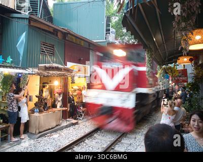 hanoi-Vietnam-10. August 2019, Touristen drängen die Gleise, während ein rasanter Zug durch Hanois enge Bahnstraße (phố Đường Tàu) fährt. Ein berühmter und c Stockfoto