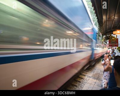 hanoi-Vietnam-10. August 2019, HANOI, VIETNAM - Touristen beobachten, wie ein rasender vietnamesischer Zug gefährlich nah an der schmalen Bahnstrecke dist vorbeifährt Stockfoto