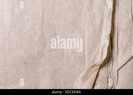 Strukturierter beigefarbener Kraftmaulbeerpapierhintergrund mit Falten und natürlicher Oberfläche. Vintage-Pergamentstruktur perfekt für Designprojekte. Stockfoto