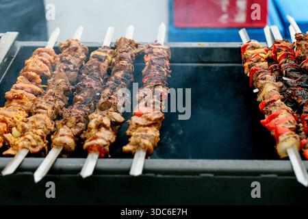 Köstliche Fleischkebabs mit Gemüse, das auf heißem Grill gegrillt wird. Saftige Spieße mit roten Paprika, die auf dem Grill kochen. Street Food Sommer Outdoor Cooks Stockfoto