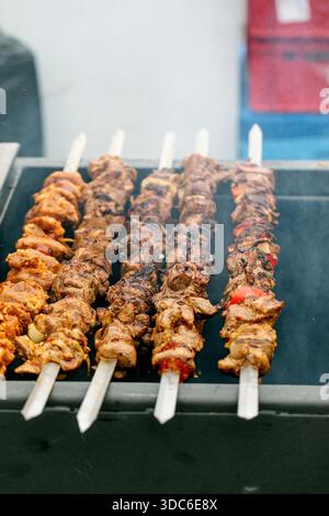 Köstliche gegrillte Fleischkebabs mit Gemüse auf Holzspießen. Nahaufnahme von saftigen Grillfleischstücken mit Paprika, die auf heißem Grill kochen. Stockfoto