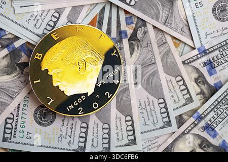 KIEW, UKRAINE - 13. DEZEMBER 2025 Trump Goldmünze auf großen Mengen von US-Dollar-Banknoten Stockfoto
