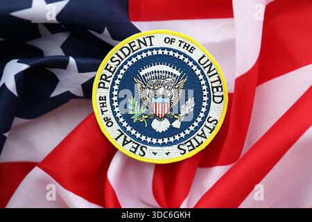 KIEW, UKRAINE - 13. DEZEMBER 2025 Siegelaufkleber des Präsidenten der Vereinigten Staaten auf den Vereinigten Staaten von Amerika gefaltete winkende Flagge mit Sternen und Streifen in Nahaufnahme Stockfoto
