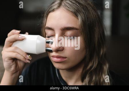 Sanfte Frau verwendet leise Nasenspray während der beruhigenden Abendroutine Stockfoto