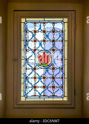 Ein elegantes Buntglasfenster mit Blumenmuster. Die lebendigen Farben und das komplizierte Design verleihen jedem Raum einen Hauch von Schönheit und Kunstfertigkeit und verleihen ihm einen ästhetischen Reiz. Stockfoto