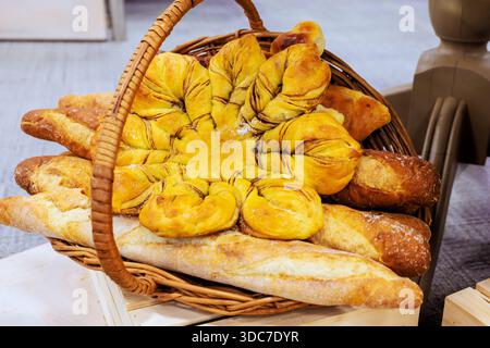 Gewebter Korb verschiedene Brotsorten mit einzigartigen Formen, goldenen Krusten, die lokale Backtraditionen zelebrieren. Stockfoto