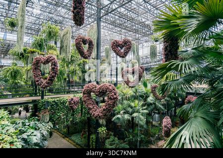 Pataya, Thailand - 1. Mai 2023 üppiger botanischer Innengarten mit herzförmigen Blumenarrangements, die von der Decke hängen und von lebhaften Farben umgeben sind Stockfoto