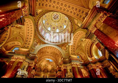 Das Innere der Stephansbasilika in Budapest mit einer kunstvollen Kuppeldecke, vergoldeten Verzierungen, Marmorsäulen und historischer Kirchenarchitektur Stockfoto