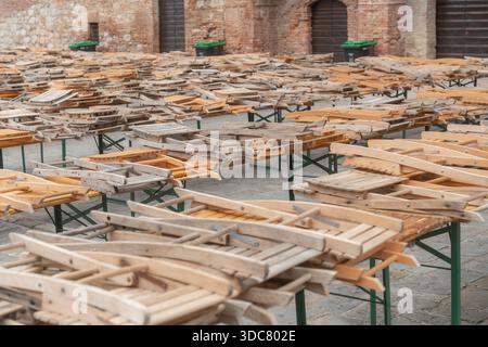 Holztische mit gestapelten Holzstühlen in Reihen. Restaurantmöbel im Freien für Lagerung oder Einrichtung vorbereitet Stockfoto