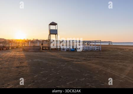 Eine wunderschöne Sonnenaufgangsszene an einem leeren Strand mit einem Rettungsschirmturm und angeordneten Holzunterkünften, die Ruhe und Gelassenheit hervorrufen. Kaspisches Meer Co Stockfoto