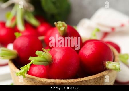 Frische Radieschen in Schüssel auf verschwommenem Hintergrund, Nahaufnahme Stockfoto