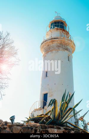 Weißer Leuchtturm an einer felsigen Küste unter klarem blauem Himmel mit hellem Sonnenlicht und mediterraner Atmosphäre. Paphos, Zypern. Stockfoto