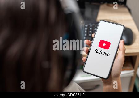 Eine nicht erkennbare Teenagerin hält ein Mobiltelefon mit dem Youtube-Logo auf dem Bildschirm Stockfoto