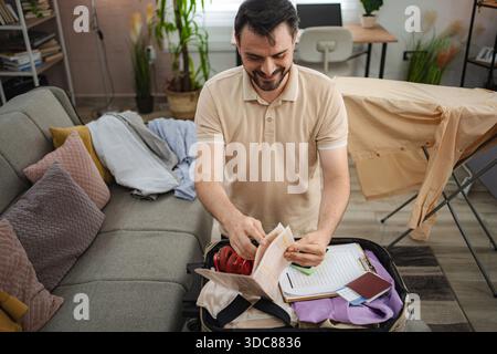 Mann packt Koffer und überprüft die Reisedokumente zu Hause Stockfoto