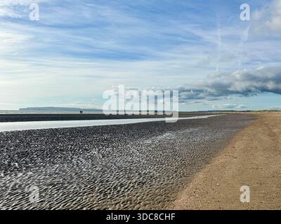 Camber Sands, East Sussex – ein riesiger, gekräuselter Strand bei Ebbe, mit Gezeitenbecken und weit entfernten Wanderer Stockfoto