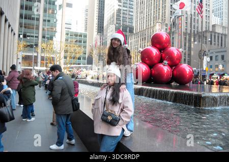 Die Leute machen Fotos vor großen Weihnachtsdekorationen in einem Brunnen vor der Radio City Music Hall in Manhattan, New York City. Stockfoto