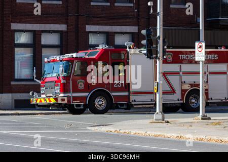 Kanada, Québec, 11. Oktober 2025: Roter Feuerwehrwagen parkt in der Nähe eines Backsteingebäudes an einer ruhigen Stadtstraße Stockfoto