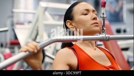 Fitness-Frau, die Pulldown-Training im Fitnessstudio ausübt. Eine Frau, die im Fitnessstudio auf einem Latgerät Sport macht. Eine Frau führt lat Pulldowns durch, um A zu stärken Stockfoto
