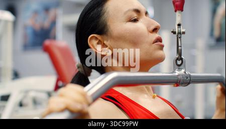 Fitness-Frau, die Pulldown-Training im Fitnessstudio ausübt. Eine Frau, die im Fitnessstudio auf einem Latgerät Sport macht. Die Frau führt lat Pulldowns durch, um zu stärken und Stockfoto