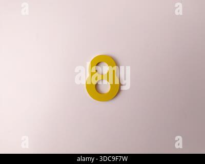 Das Bild zeigt eine gelbe, stilisierte Zahl 8 auf weißem Hintergrund. Stockfoto