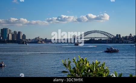 Fähren und Schnellboote fahren im Hafen von Sydney, eingerahmt von der berühmten Oper und der großen Harbour Bridge. Stockfoto