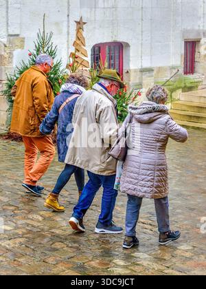 Zwei ältere Paare, die an einem regnerischen Tag gemeinsam durch die Stadt spazieren gehen - Loches, Indre-et-Loire (37), Frankreich. Stockfoto