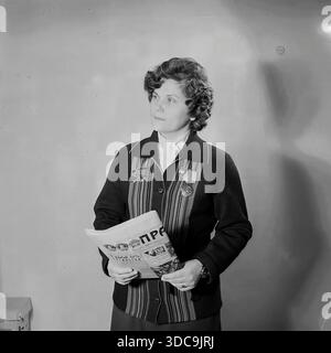 Slawjansk, Ukrainische SSR, UdSSR - 1981: Archivporträt von Ljudmila Wiktorovna Schudinova, stellvertretender und Karbonisierungs-Betreiber im Nowosodowski-Werk. Sie posiert mit einer „Prawda“-Zeitung und trägt eine Jacke mit Arbeitsmedaillen und repräsentiert die Elite der Stadt. Dieses Bild fängt die idealisierte Figur einer Arbeiterin und Politikerin ein und symbolisiert die vereinigung schwerer Industriearbeiten und bürgerlicher Pflichten in der friedlichen Donbass-Region während der späten Sowjetzeit. Stockfoto