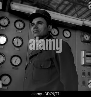 Slaviansk, Ukrainische SSR, UdSSR - 1981: Archivporträt des Abgeordneten Rypalenko, der in einem Kontrollraum posiert. Er trägt einen Schutzhelm mit Lampenhalterung und Arbeitskleidung und steht selbstbewusst vor einem massiven Panel voller analoger Anzeigen und Schalter. Das Bild spiegelt die technische Expertise und den stoischen Charakter der sowjetischen Arbeiterklasse wider. Diese Szene spiegelt die industrielle Macht und Stabilität der friedlichen Donbass-Region während der späten Sowjetzeit wider. Stockfoto